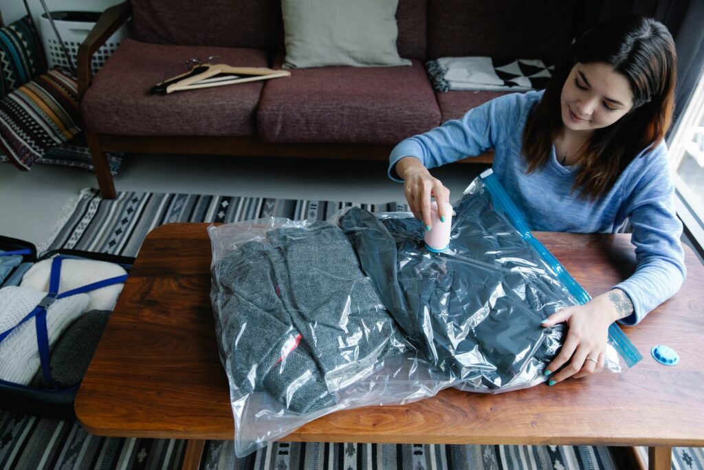 Embrace the Magic of Vacuum Storage Solutions - A Woman Vacuum Packing Clothes on a Table