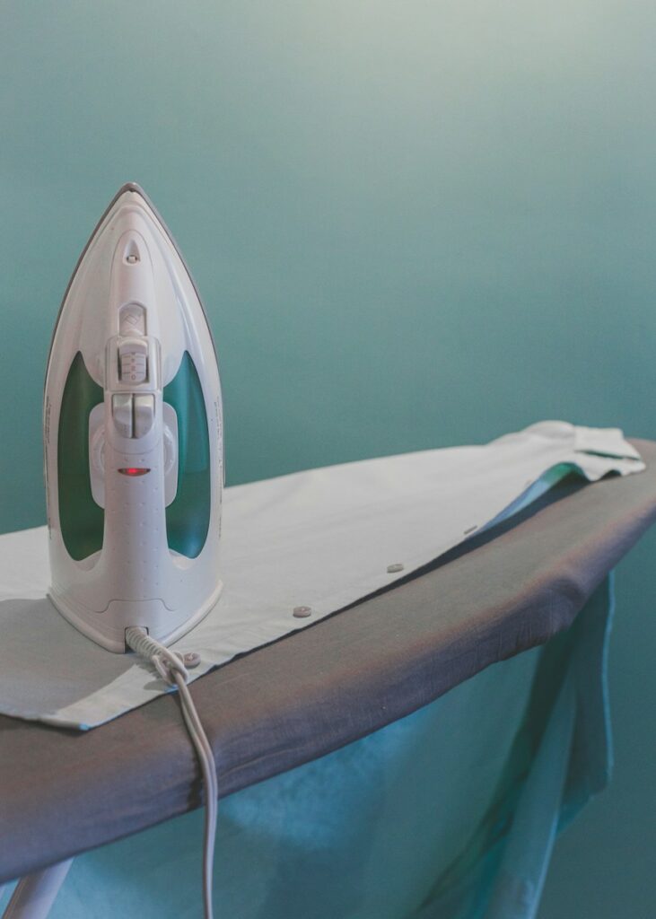Utilizing Ironing Boards with Good Padding for Smooth Results - white and teal steam clothes iron plugged on ironing board