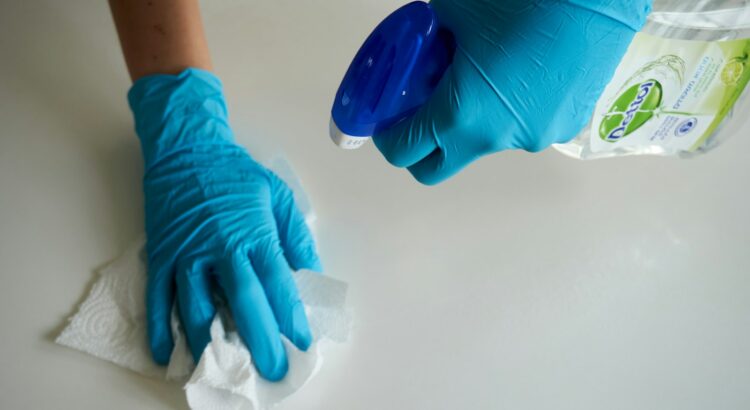 cleaning tips - person in blue gloves holding cleaner